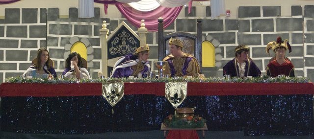Queen Kayla Oelschlaeger leans over to talk to the feaste's king, Justin Moss, before the start of Friday night's Madrigal Feaste. Sitting at the main table reserved for the Royal Court were the two princesses (left) Katy Kolman and Lydia Thao, Drew Scates, the prince, and Christopher Jordan, the court jester. This was the first year that the event was held at the Tonganoxie Middle School.