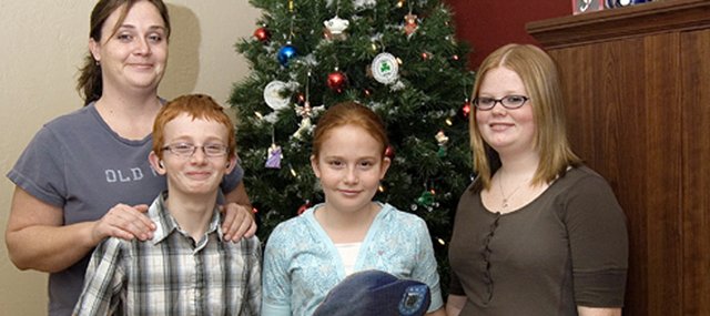 Leanne Peel, left, stands with her three children, who are holding a cardboard cutout of their father, Joe Peel. This is the first Christmas the children won't spend with their father, who is serving as a U.S. Army Specialist in Iraq. The children, from left, are J.D. Peel, Haleigh Peel and Torrie Evans.