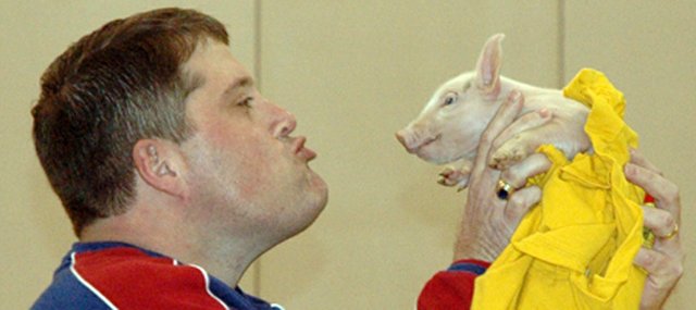 Kerry Brungardt, principal of Lansing Middle School, kisses a pig Friday in front of the entire school population during the final pep rally of the season. Both Brungardt and assistant principal Brooks Jenkins agreed to kiss a pig if the students raised more than 2,000 cans of food during the LMS student council's annual can drive.