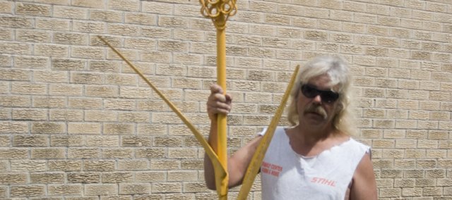 Local chainsaw artist Russ Ehart, displays his latest work, an 8 1/2 foot tall metal sculpture of a wheat stalk May 20. Ehart, who is used to working with wood, said it took him about a week to finish the sculpture because he had to buy a lot of new tools so he could work with the new medium. The sculpture is for Stanley Itzen of Hillsboro. Another project Ehart has been working on is a chainsaw carvers competition that will be held at the Leavenworth County Fairgrounds and will be a part of Tonganoxie Days. Ehart said he has about six carvers that are ready to participate. He has invited the carvers to bring pieces to sell and has arranged for all of the pieces made during the competition to be sold at an auction that will begin at 4 p.m. the same day.