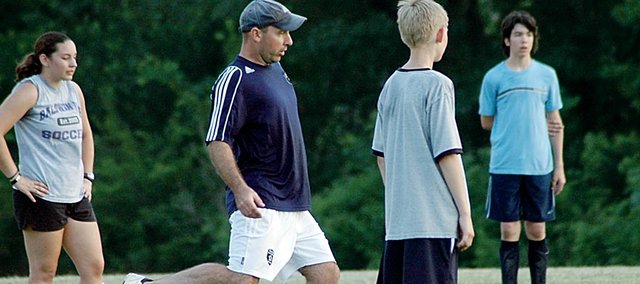 Matt McCune, center, demonstrates the proper technique for passing a soccer ball during his five-day summer camp last week. McCune, a Baldwin High School graduate, will be the head coach of the Bulldogs for the first time this fall. He held his summer camp last week to teach fundamentals and meet the players.