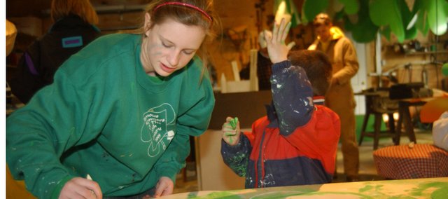 Madison Fangman, 13, De Soto, paints a message that will be part of the O’Connor family float in the Kansas City St. Patrick’s Day Parade, while her 6-year-old brother Max shows of his emerald green hand he painted while helping with the decorations. The family has a long history with the parade and hopes to repeat as the grand prize winner.