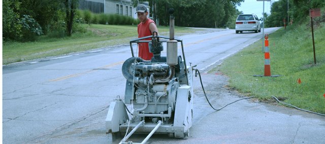 Joe Lowman of Bazin Sawing and Drilling, Louisburg, cuts bad curb and gutter from 83rd Street on Tuesday as the $900,000 resurfacing of the street from Kill Creek Road to the east city limits gets started. Next week, the existing asphalt from Kill Creek to Gardner roads will be removed and work will start to rebuild the road base.
