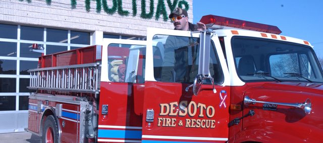 Capt. Bob McCoy climbs out of the cab of a pumper truck Friday at the De Soto Fire Department. Less than 10 hours later, the department merged with Johnson County Rural Fire District No. 3 to form the Northwest Consolidated Fire District. The department’s new logo shown above the photograph will replace those on trucks in the coming months.