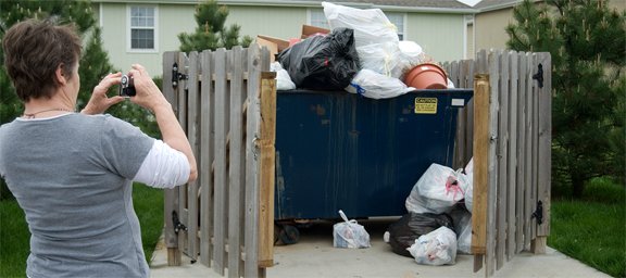 Linda Brake takes a photo of the pile of garbage that has built up inside the one dumpster for Sundance Apartments. Brake and other apartment residents said the property managers have been neglecting their responsibilities to their tenants. An official from Honey Creek Disposal Inc., who services the apartment building said the property managers were months behind on payment so they stopped picking up the garbage.