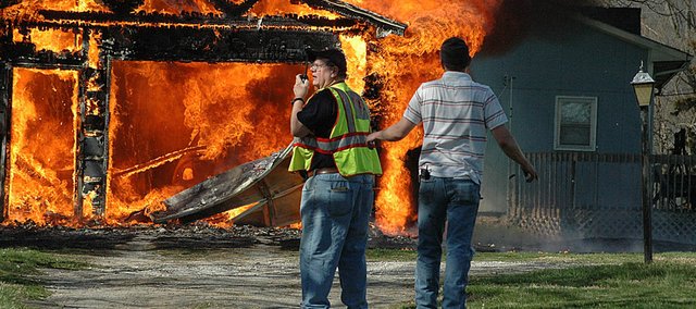Baldwin City Fire Chief Allen Craig, left, radios orders to firemen at the scene of a garage fire on Elm Street Wednesday afternoon. The garage was engulfed in flames by the time firefighters arrived and it was a total loss, along with a car that was parked inside. The cause of the blaze is under investigation.