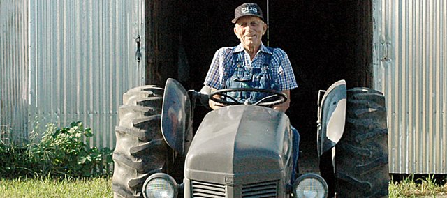 Max Moore sits on his 1950 Ferguson tractor after pulling it out of one of his barns on his farm north and west of Baldwin City Tuesday morning. Moore was undefeated on his favored Ferguson during the years he entered the Vinland Fair tractor pull. The 92-year-old will be there with it Friday to be recognized.