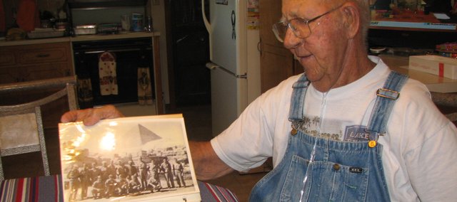 Harry Kelley, of Basehor, flips through a scrapbook, displaying a photo of him and other World War II prisoners of war in Cairo, Egypt, after being freed at the end of the war. Kelley said one other person in the photo was still alive. Kelley will celebrate his 90th birthday at 3 p.m. Saturday at the Basehor VFW post.