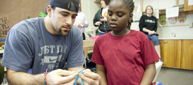 Mike Rivera, a former Shawnee Mission Northwest and Kansas University football player, left, sits with Boys and Girls Club member Frida Danburno as the two work on a crochet project. Rivera volunteered his time with Lawrence youths on Wednesday, April 13, at Hillcrest Elementary. Rivera currently is a linebacker with the Miami Dolphins.