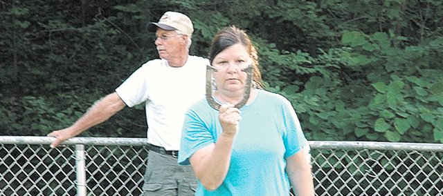 Chris Hagger of Shawnee lines up her pitch at the South Park horseshoe courts while visiting player Chuck Blunck of Boise (background) awaits his turn. The Bonner Springs Twister’s Horseshoe Club has been playing doubles games every Tuesday night since mid-April and will begin singles games in early July.