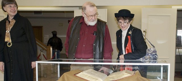 Kay Bradt, Baker University director of library services watches as Tom and Sue Ann Kleist view the 1611 King James Bible featured on the cover of this month’s National Geographic Magazine. The notoriety from the cover photo has increased interest in the Bible and others in the university’s Quayle Bible Collection.