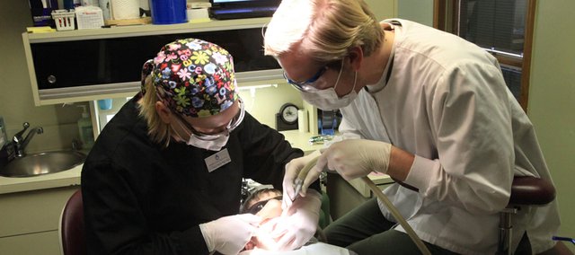 From left, Dr. Cheryl Biesterfeld, and dental assistant Steve Frost, provide care Friday, Feb. 3, 2012, for Calum Ochsner 8, Lawrence, at the Douglas County Dental Clinic, 316 Maine. The clinic provided free dental care for uninsured children Friday as part of "Give Kids A Smile Day." The difficulty for Baldwin City parents of taking off work to take advantage of such programs was one of the challenges in a Douglas County health assessment released Monday.