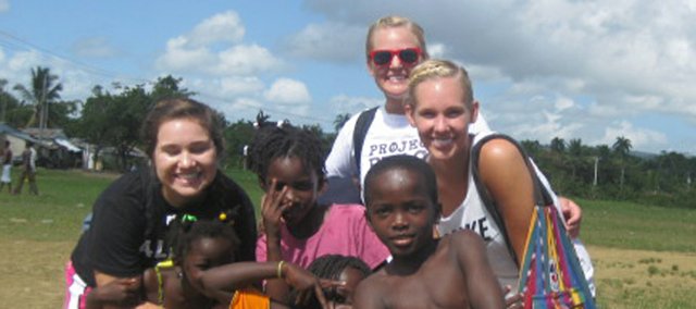 Brooke Morgan, left, and sisters Claire and Alyssa Peterson, top right. pose with some of the children they met on a recent mission trip to the Dominican Republic. The three Baldwin City young women are still working to end human exploitation in that country by selling jewelry that supports the Go Mad Ministry.