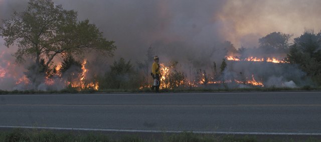 With plenty of fuel from drought conditions, a wildfire burns along U.S. Highway 56 as a fireman walks along the highway. Firefighters from multiple departments fought three fires July 15 along the highway on the west edge of Baldwin City. The summer heat wave and drought, which persists, was the No. 2 local story of 2012.
