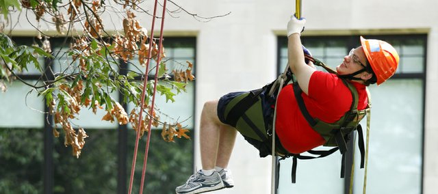 Devan Glenny, a college senior from Lebanon Valley College in Annville, Pa., leaves his wheelchair on the ground as he ascends into a tree Thursday on the Baker University campus. Eight research interns were selected from across the country to participate in a 10-week, canopy-research project funded by the National Science Foundation. The interns will be climbing the trees at various heights to collect moss and lichen samples for measuring the density and diversity of microscopic animals called tardigrades. Glenny, who is interested in pursuing a career that involves field research, says he was drawn to the project when he found out it was open to students with wheelchairs.