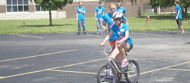 ICan Shine camp floor leader Kenan Brod runs along side of Faith Wallis at a Friday session of the ICan Shine bicycle camp on a Baldwin High School parking lot. With the help of 88 volunteers, 27 individuals with physical and/or developmental disabilities learned to bike at the five-day camp.