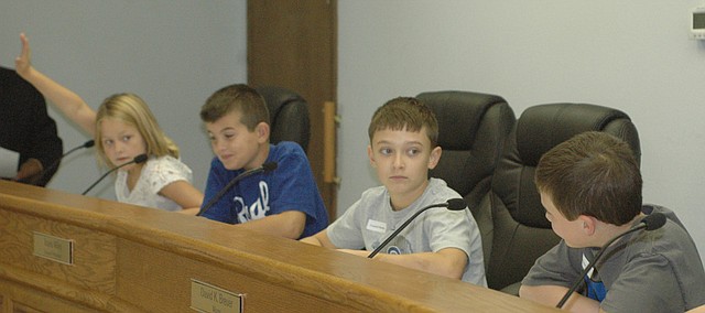 Georgia Moore raises her hand to speak as a council member Wednesday morning during a mock city council meeting with fellow Basehor Intermediate School third graders Christian Locke, Nicholas Hotujac, and Talin Turner, who was playing the mayor.