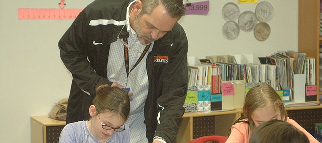 Don Cooley, BSE second grade teacher, helps out a student in Ea Trumbo's fourth grade class after popping in on his lunch break. Trumbo said Cooley is known for dropping into classrooms throughout the school, and like the other male teachers at BSE, serves as a good role model for the students.