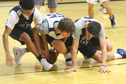 Three members of the Mill Valley High School boys' basketball team fight for a loose ball during a practice Thursday night at Mill Valley High School.