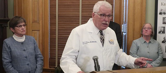Kansas Health and Environment Secretary Lee Norman, center, answers questions about a COVID-19-related death of a man in his 70s in a Kansas City, Kan., area nursing home, the state's first fatality linked to the coronavirus, Thursday, March 12, 2020, at the Statehouse in Topeka, Kan. Watching are Gov. Laura Kelly, left, and Laura Howard, right, the state's secretary for aging and disability services. (AP Photo/John Hanna)