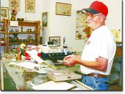 Downtown antique shop owner Leland Massey stops to chat with a
customer in his Eudora store. After three years in business, Massey
will close shop July 1 due to declining sales.