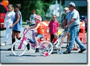 Riding through Tonganoxie Day events on wheels, Allie McCracken, 5,
pedals her bicycle. Behind her, her father, Chad McCracken, pushes
Allie's 2-year-old brother, Tanner McCracken in a stroller.