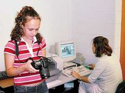 De Soto High School junior and school newspaper staff writer
LaTisha McIntyre checks the photos she took on one of the schools
digital cameras as Ashely Henney works photographs on a computer.
Henney, a junior, is the newspaper's photo editor.