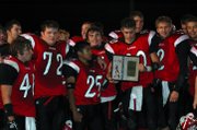 Lansing football players, from left, David Hartel, Jeff
Collins, Aaron Sexton, Neal Watson and John Tytla gather around their
bidistrict championship plaque. The Lions defeated De Soto, 10-7,
Tuesday night and advanced to the regional playoffs for the first time
since 1983.