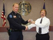 Lansing's new police chief, Steve Wayman, left, accepts the chief's badge from City Administrator Mike Smith during a ceremony Friday morning at City Hall. Wayman was promoted from his post as captain with the resignation of Chief John Simmons, who is moving to the Fairway Police Department.