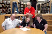 Jessica Kane, center, signs her letter-of-intent to play softball at Kansas City Kansas Community College. The senior pitcher was joined by her parents, Rob and Nancy Kane, sitting, and Lansing High coach Terry Cornett.