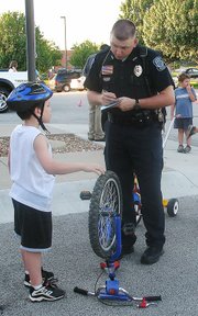 Lansing Police Officer Michael Heuer registers the bicycle of Brian Orkwis, 8, Lansing, at Monday's bike rodeo. Officers and Scout leaders also taught bike-riding safety.