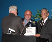 While receiving a pin from Gene Young, left, Dale Bohannon shows off the certificate designating him the Lansing PRIDE Volunteer of the Year for 2005. Mayor Kenneth Bernard, right, introduced Bohannon as the award winner during the annual Recognition Dinner on Monday at the Lansing Community Center.