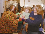 Balloon artist Nancy Dempsey puts a balloon bracelet around the
hand of 19-month-old Isabell Hamilton as Stephanie Hamilton looks
on.