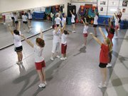 Aimee Vroman, center, a cheerleading camp instructor, corrects posture and technique during a camp held June 4 8 for members of the Lansing Middle School and Warren Middle School cheer squads at Katie's Dance Studio. Squad members practice dance and cheer routines over the summer to prepare for the coming school year.
