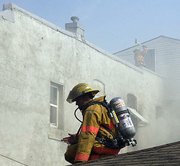 Firefighters work from the roof of the building to combat the flames spreading within 726 Shawnee St., Leavenworth.