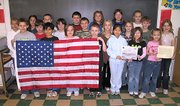 Lansing Intermediate School fourth-graders display an American flag that was flown over the U.S. Military Headquarters in Baghdad, Iraq, during Operation Iraqi Freedom. Maj. Mark Zinser, of Leavenworth, gave the flag to Barb Munsterman's class, which includes his son Chase Zinser, who is holding the flag on the far left.