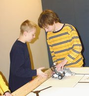 LTMS seventh-graders Philip Kaul, left, and Parker Riley carefully
place a robot they helped build as members of a nine-member
robotics competition team on a game table. Team coach Sarah Brown
built the table with the help of LTMS seventh-grader Chris Dunn.