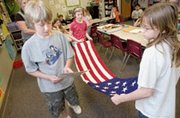 Mize Elementary School fourth-grader Nick Mullen reads instructions
to Kristen Knapp and Jordan Gorkos (right) on how to fold a flag
that came with a trunk from the Kansas Historical Society, which
provided lessons on early Kansas history.