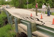 De Soto City Administrator Pat Guilfoyle (left) examines damage to
Ottawa Street Tuesday as the Rev. Jerry Vaughn and Darrel Zimmerman
look on.
