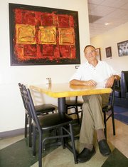 Eudora High School art teacher Gary Hinman sits next to his piece
"Act Now," currently displayed at Wheatfields Bakery, 904 Vermont
St., in Lawrence. Hinman has 20 different variations of an iconic
sliced piece of bread in mixed media.