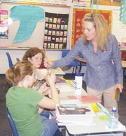 Fifth-graders November Bishop and Baillie Beebe take coaching from
instructor Niki Rheuport as they measure a plant's growth Monday
during science class. The fifth-graders travel to Rheuport for
science, but are in Megan Whitebread's homeroom again this year.