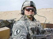 As commanding officer of the U.S. Army's 19th Material Management Team Lt. Col. Hughes keeps a lookout aboard an up-armored Humvee headed to Tal Afar, Iraq. Hughes was awarded the Army's combat action badge after helping provide security for the Iraqi National Election held Dec. 15, 2005.