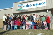 Debbie Deere, owner of A Deere Place, cuts the ribbon for the ceremonial opening of the new preschool at 1104 Industrial Street in the Lansing Business Center off Gilman Road. A Deere Place offers all-day and half-day care for children ages three to six and before and after school care for Lansing Elementary and Intermediate School students. Standing to Deere's left is Lansing Mayor Kenneth Bernard and to her right is Lansing Chamber of Commerce president Greg Madsen and her husband Kyle Deere. Some of the students and staff of the center, which moved to the new location on Nov. 1, also joined her for the ribbon cutting.