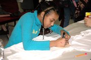 Ariana Clark, 11, draws a star on a T-shirt using a marker and stencil Tuesday during the Lansing Lions Booster Club's annual spirit T-shirt design event. About 118 Lansing Middle School students attended the free after-school event where they were also provided with drinks and snacks.
