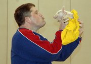 Kerry Brungardt, principal of Lansing Middle School, kisses a pig Friday in front of the entire school population during the final pep rally of the season. Both Brungardt and assistant principal Brooks Jenkins agreed to kiss a pig if the students raised more than 2,000 cans of food during the LMS student council's annual can drive.