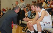 St. James Academy basketball coach Mark Huppe jokes with starters Jake Wittman and Clint McCullough during the starting lineups prior to the Thunder's game against Topeka Hayden.
