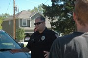 Officer Jeff Weissman talks to some area residents while responding to a littering complaint. Small towns struggle to provide competitive salaries to some employees like police officers.