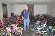 Neil Holman, Shawnee parks and recreation director, is surrounded by children's bicycles to be recycled and distributed through a program that benefits the needy and promotes cycling among younger generations.