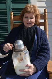 Sharon Uhler, curator of education at Shawnee Town 1929, churns butter last Friday on the front porch the living-history museum's farmhouse, part of the Shawnee Town 1929 Truck Farm that will be hosting a grand opening on May 4.
