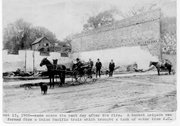 Citizens gather near the remains of buildings following the fire that destroyed several businesses in the 100 block in 1908. From the Urbin Ruddell collection.